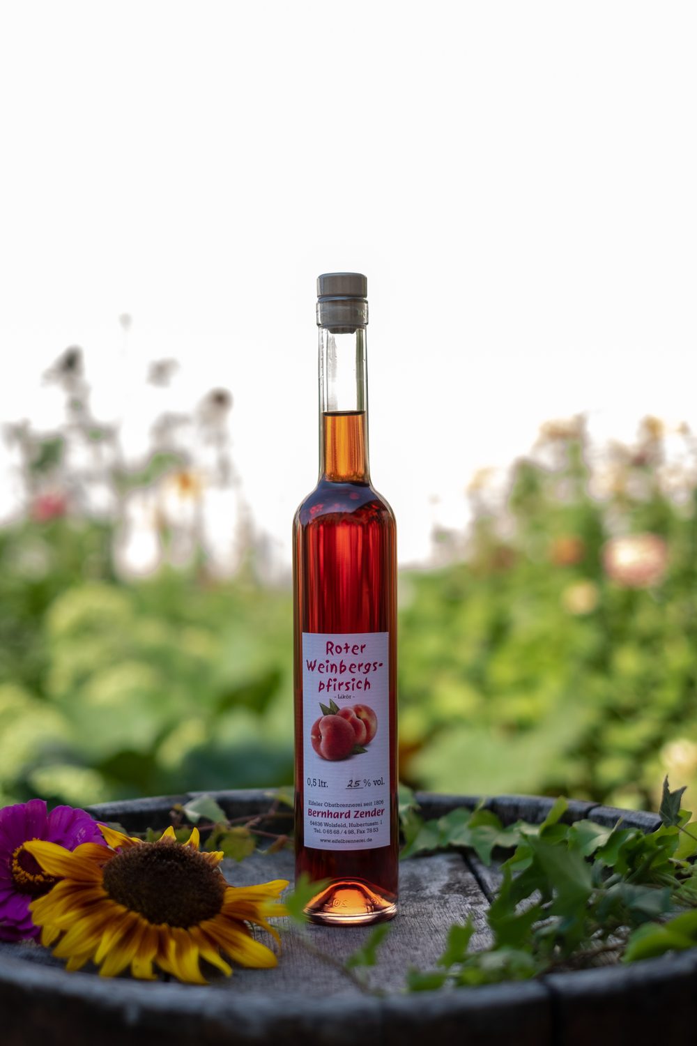 Flasche Weinbergpfirsichlikör der Eifelbrennerei Bernhard Zender auf einem Holzfass